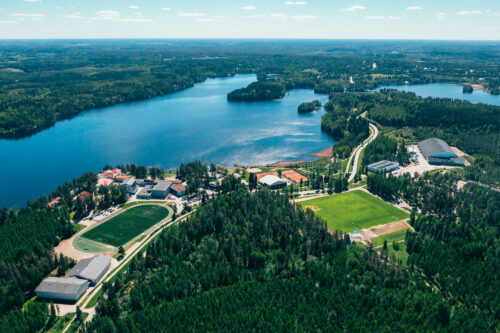 Pajulahden ilmakuvassa näkyy Iso-Kukkasen järvi, Pajulahden kentät ja rakennukset sekä paljon ympäröivää metsää.